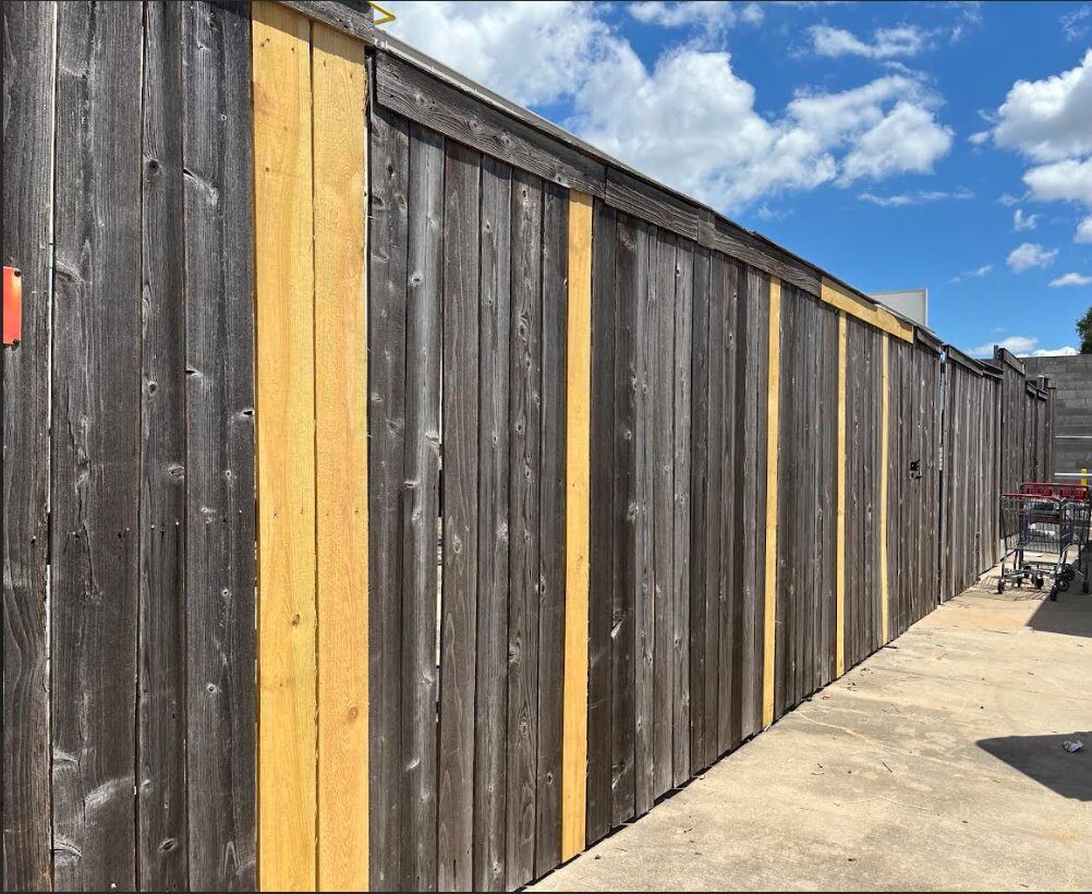 Cedar perimeter fence with damaged boards spot-replaced in fresh wood, preserving the existing fence structure