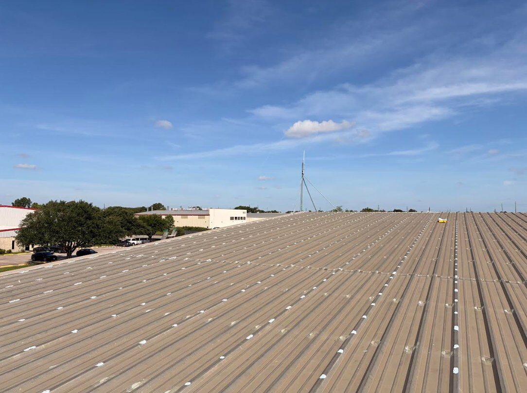 Wide view of commercial standing-seam metal roof with every fastener individually sealed across the roof field, FST proactive maintenance