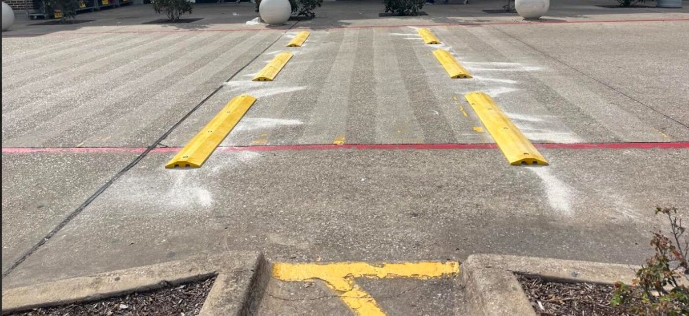 Pedestrian crossing speed bump installation between parking lot and storefront, slowing drive-through traffic